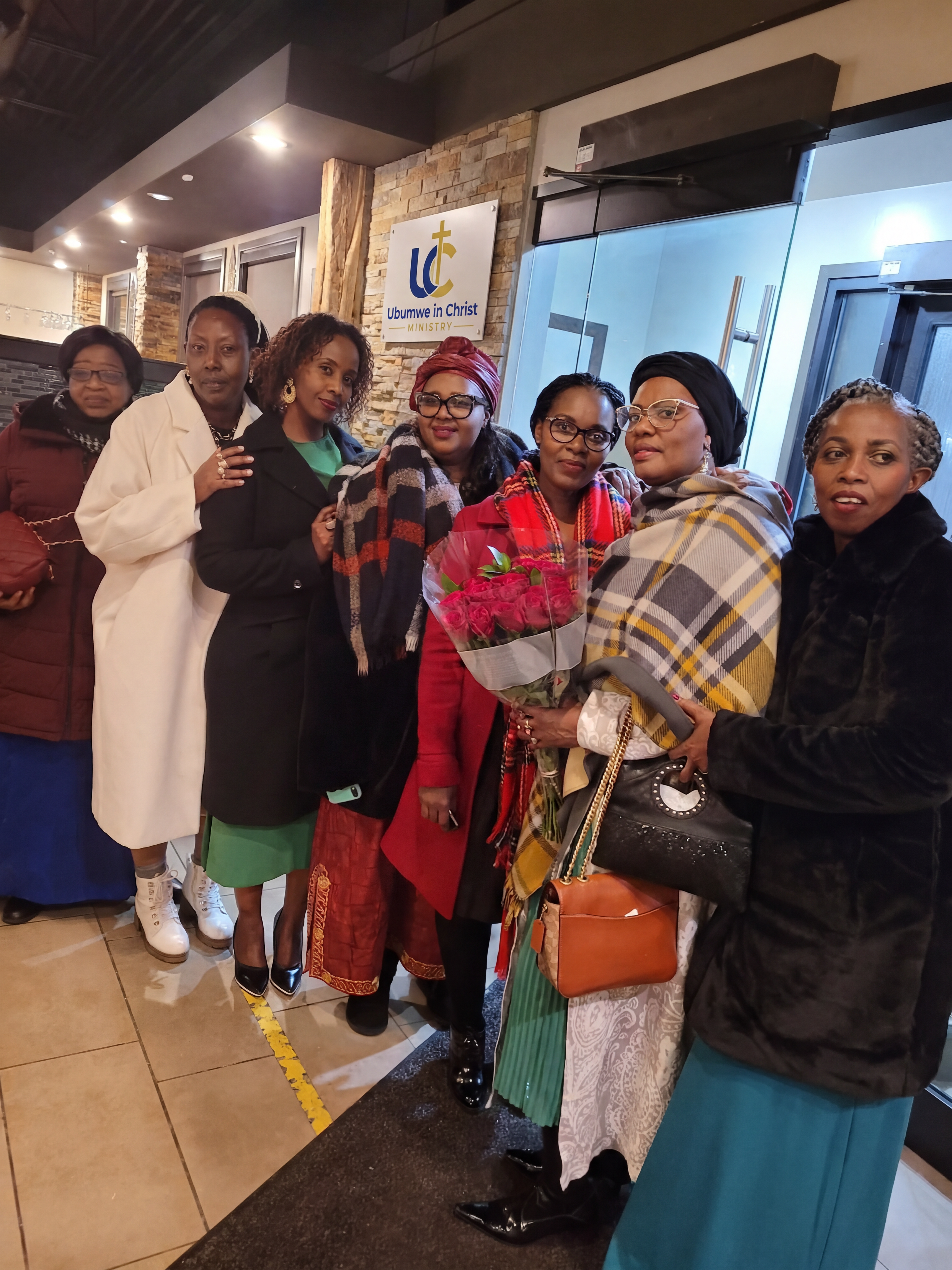 Members of Ubumwe in Christ Ministry gathered together beneath the ministry sign